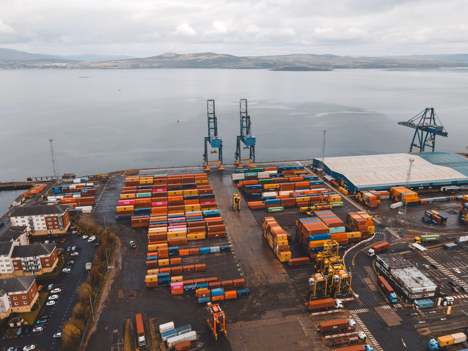 Aerial view of a busy container port with cranes and stacked cargo containers
