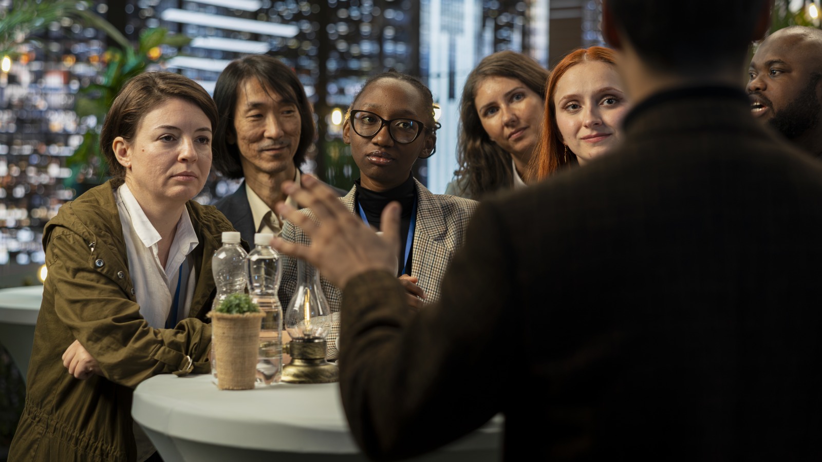 A group of founders around a high-top table listening to a speaker at an evening meetup