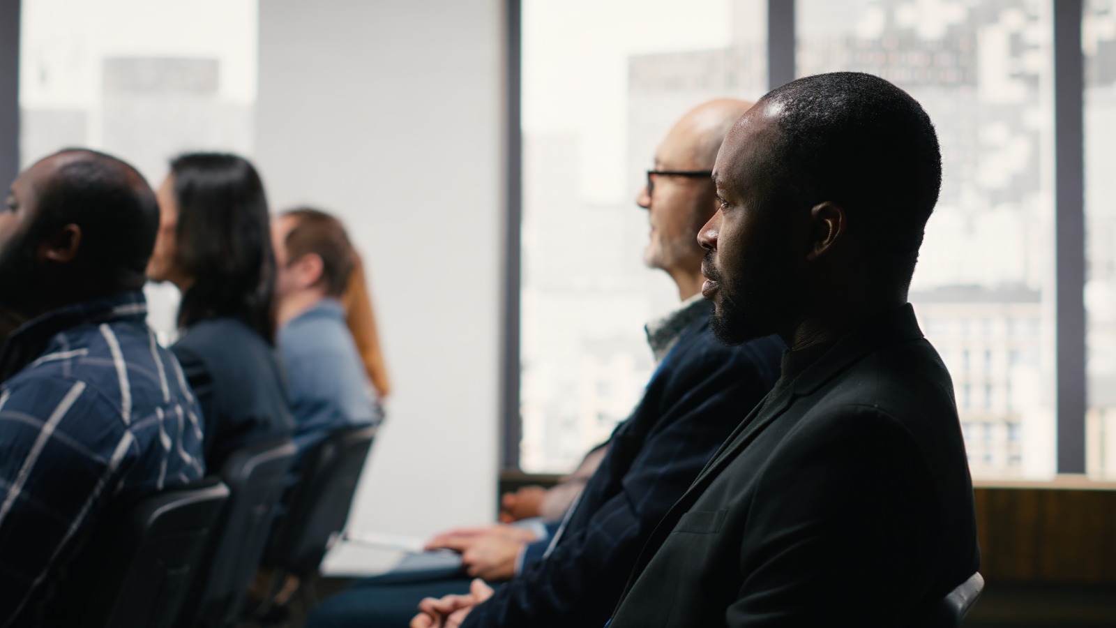 Professionals seated in an audience listening to a speaker at a business forum
