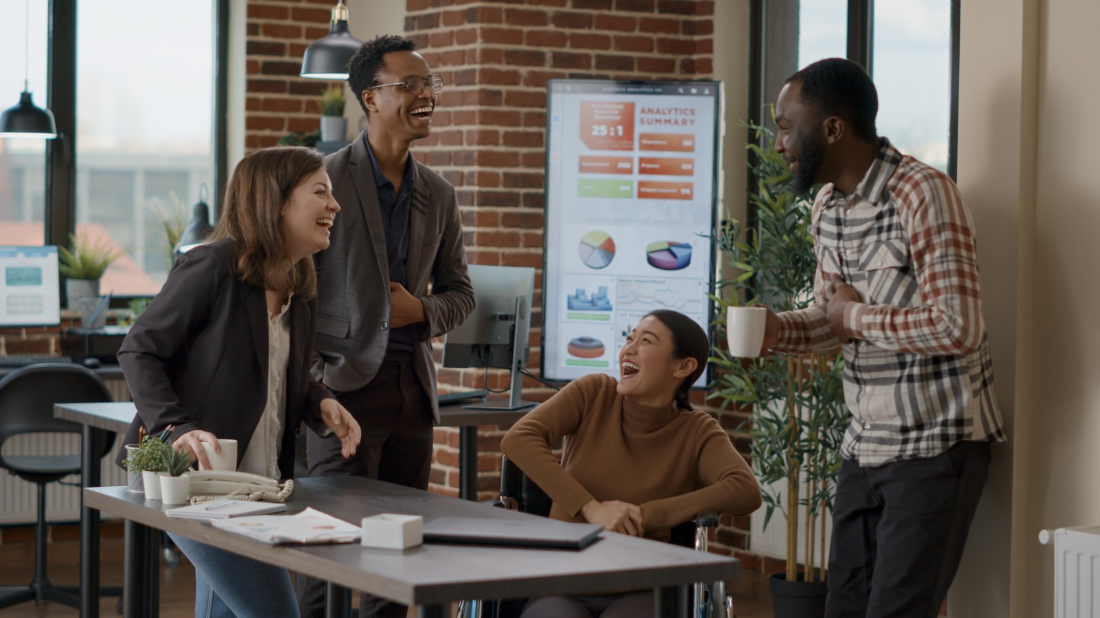 Diverse startup team laughing and planning together in a brick-walled office